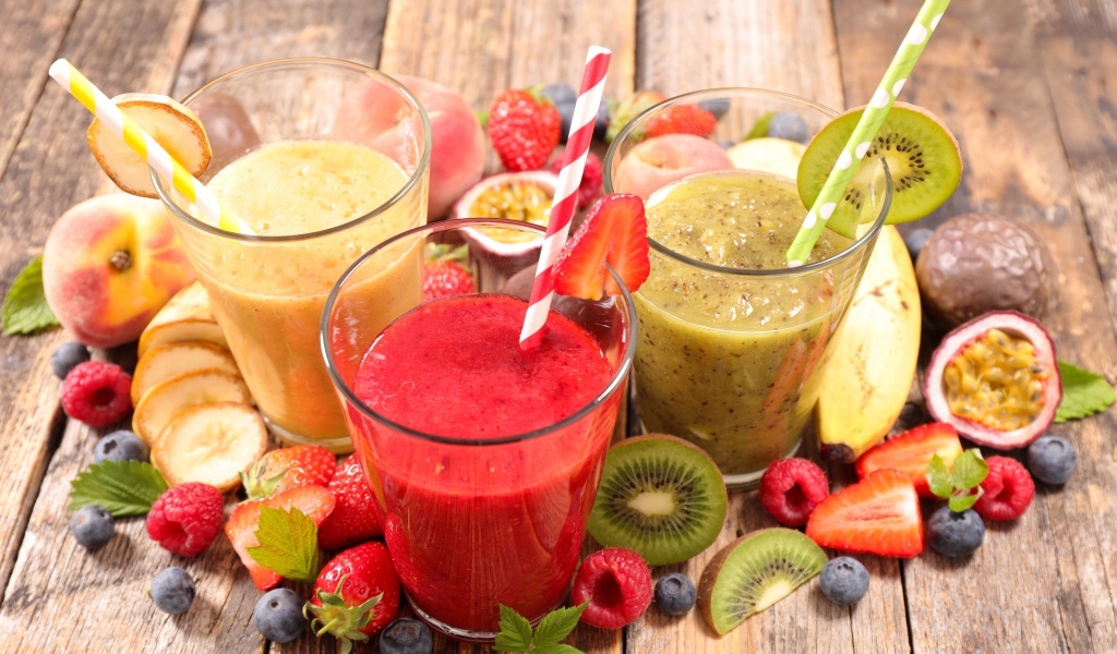 Смузи в стаканах с трубочками на столе со свежими фруктами