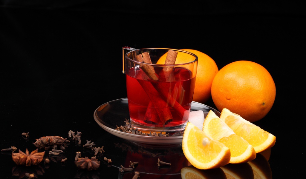 Чай с корицей и кусочками апельсина на черном фоне