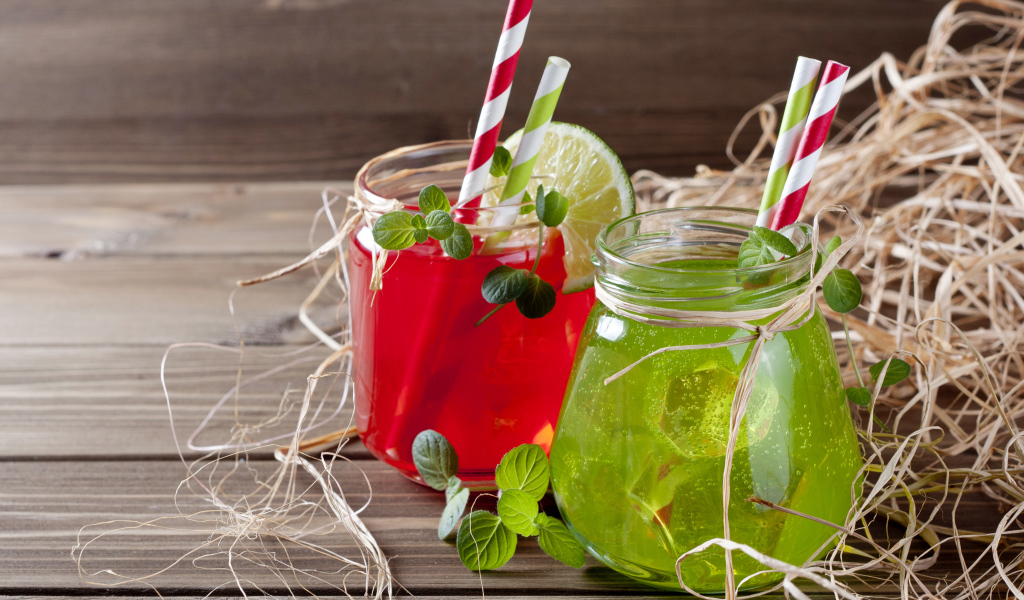 Две банки с коктейлями на деревянном столе с соломой