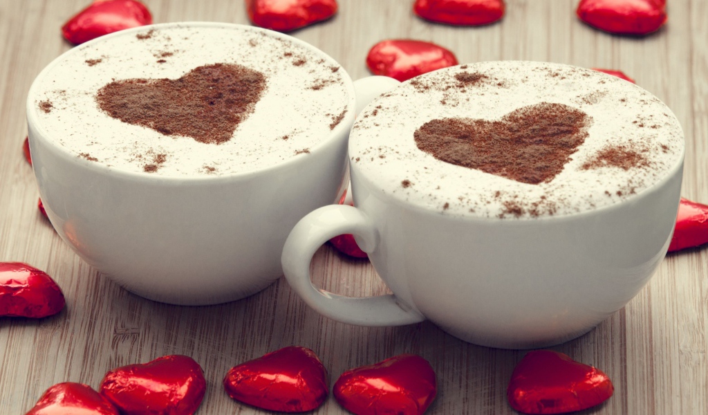 Две чашки кофе на столе с шоколадными конфетами в форме сердца