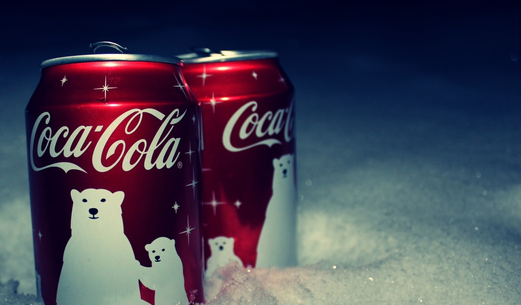 Две красные банки напитка Кока Кола стоят на снегу