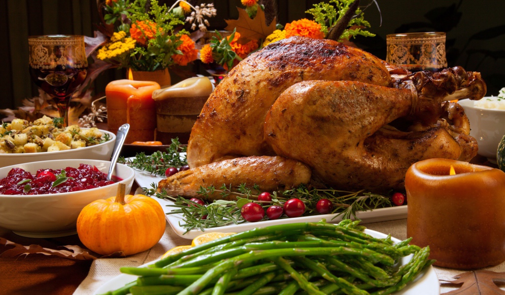 Аппетитная запеченная курица с зеленой спаржей и угощениями на праздничном столе