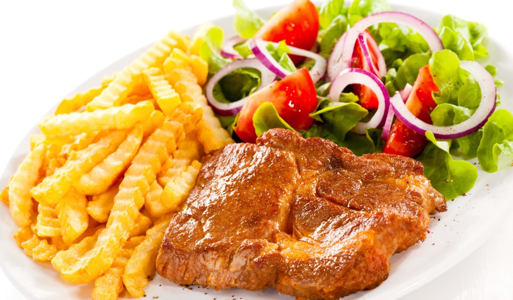 Аппетитная отбивная на тарелке с картофелем фри и салатом