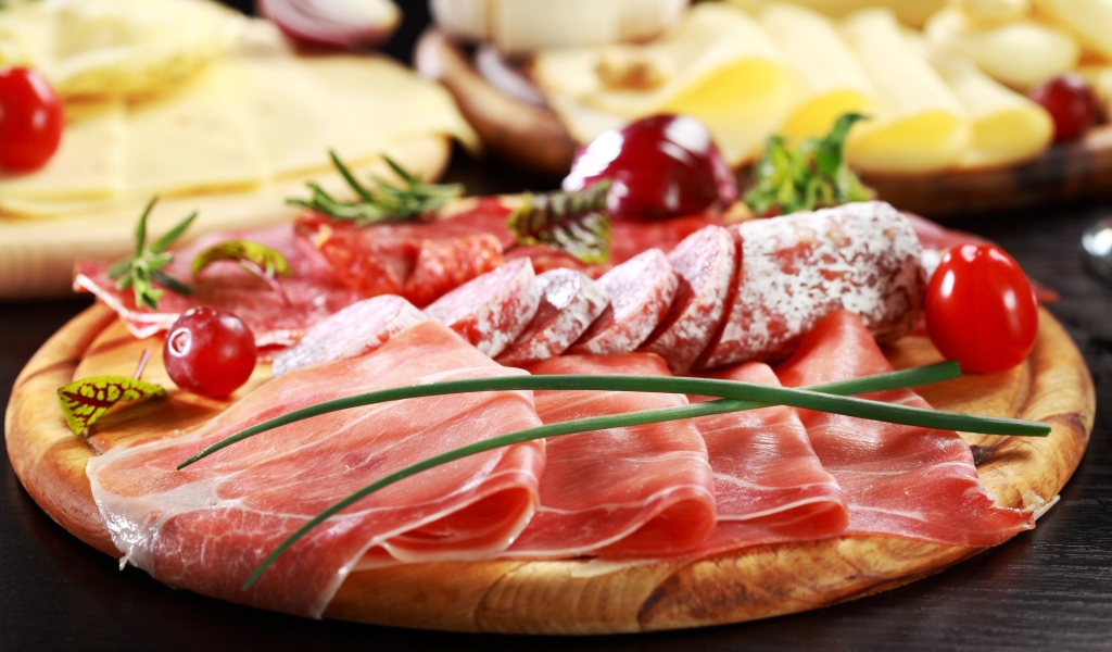 Аппетитная мясная нарезка на деревянной доске с зеленым луком