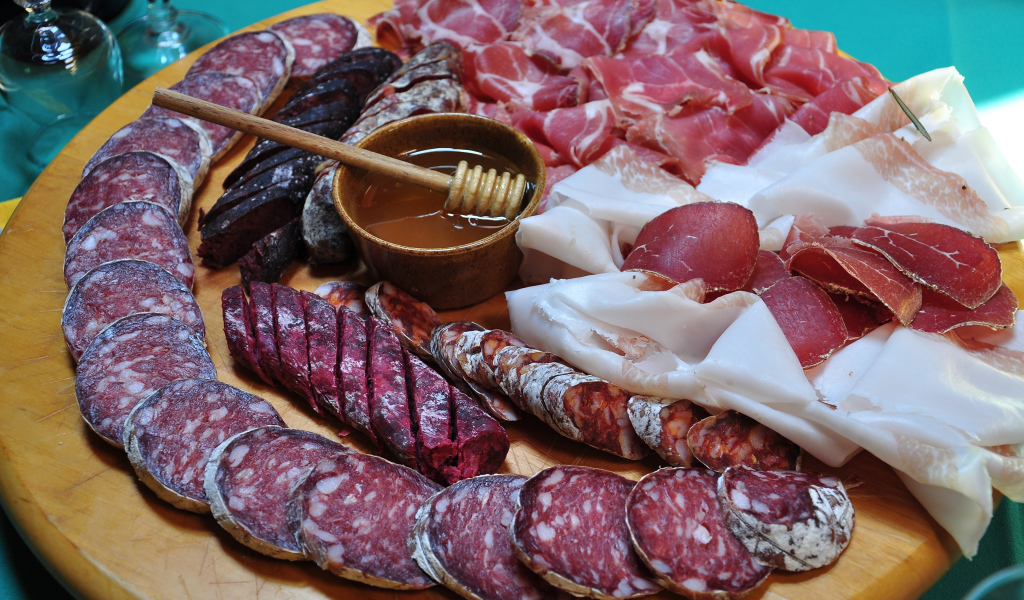 Аппетитная мясная нарезка на разделочной доске с медом