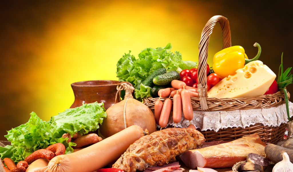 Аппетитные мясные продукты на столе с корзиной овощей