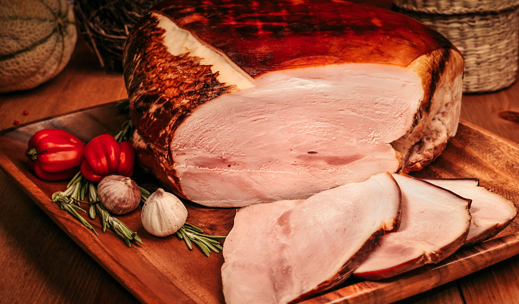 Аппетитный кусок ветчины с перцем и чесноком на доске