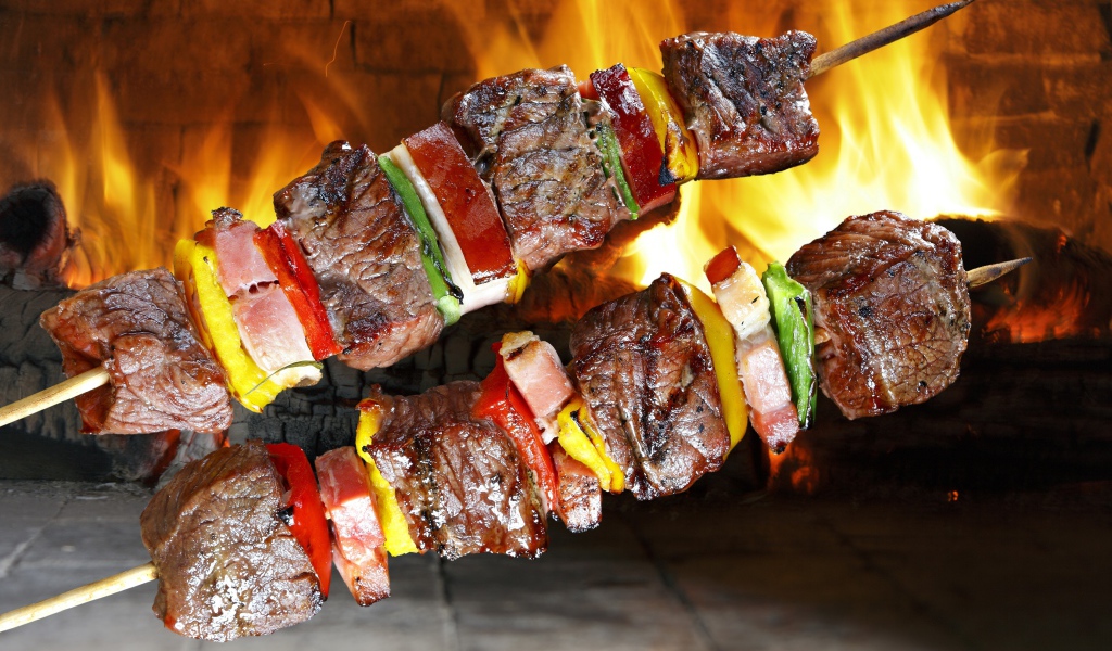 Аппетитный шашлык с овощами на фоне огня