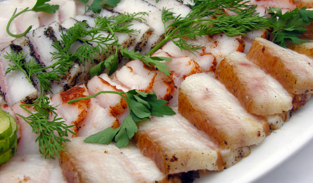 Аппетитное нарезанное копченое сало с зеленью 