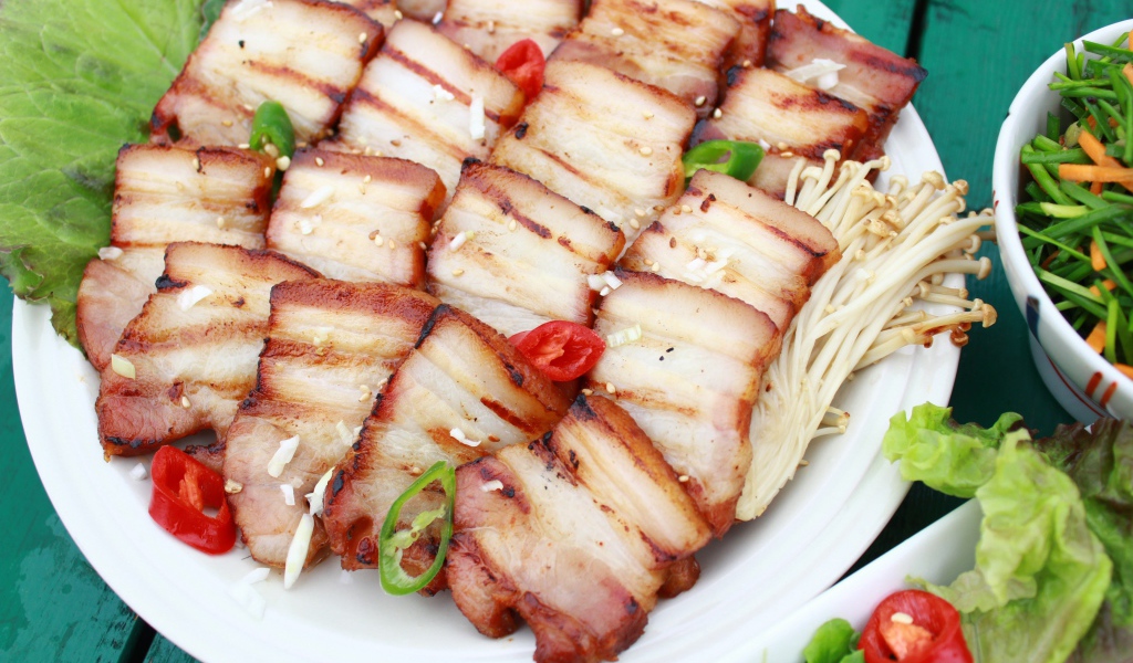 Аппетитное копченое сало на столе с овощами