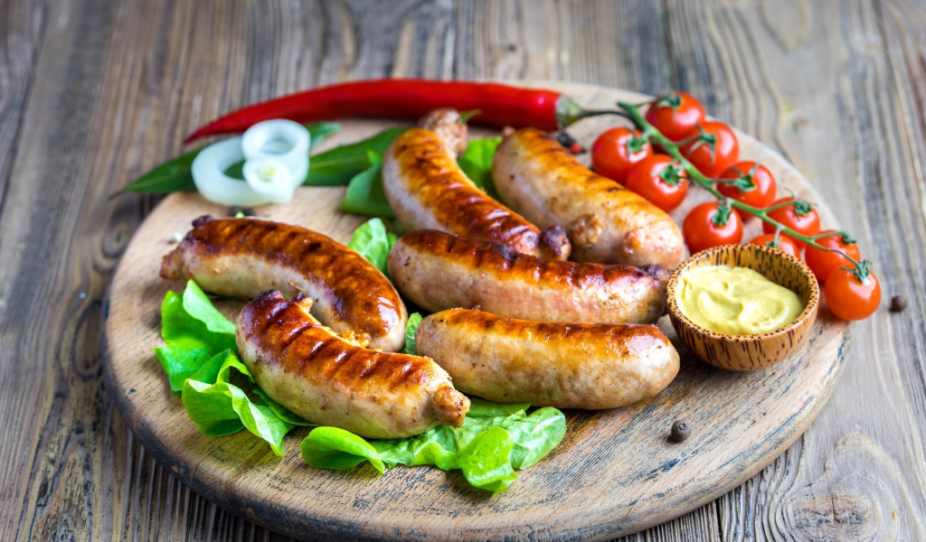 Сосиски барбекю с красным перцем и помидорами на разделочной доске