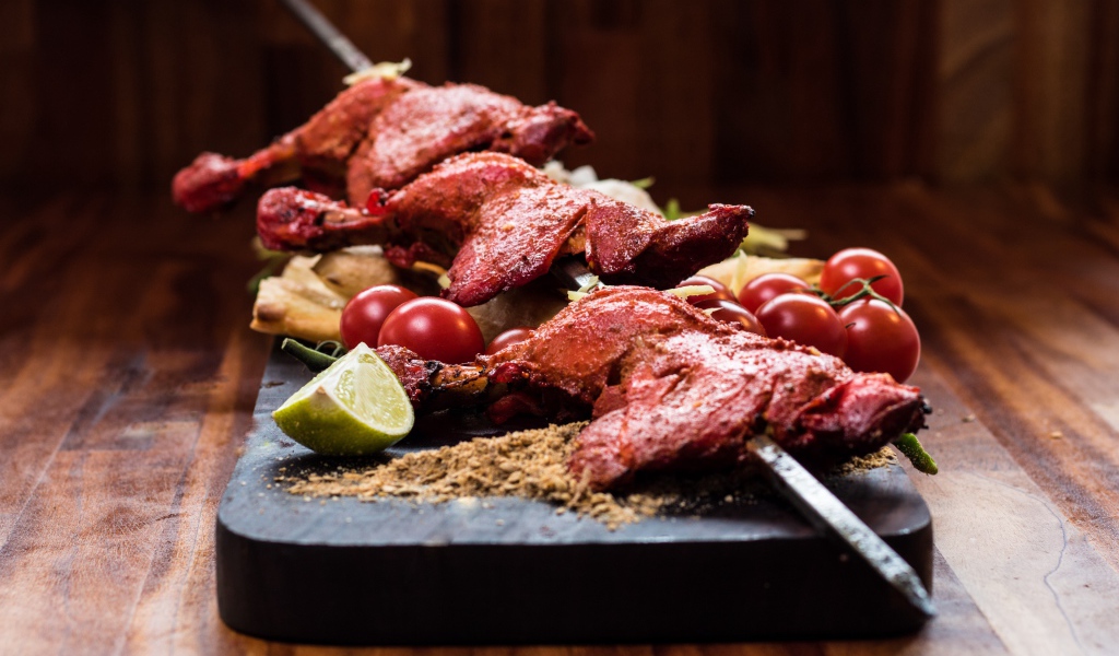 Курица жареная на шампурах на столе с овощами 