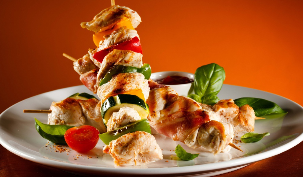 Куриные шашлыки с овощами на белой тарелке