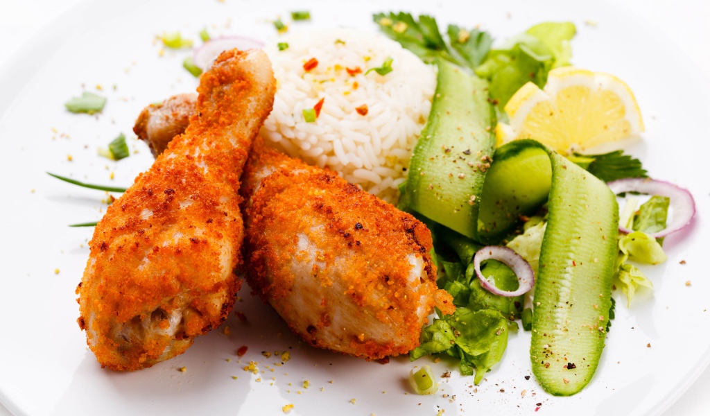 Куриные ножки с рисом и салатом на белой тарелке