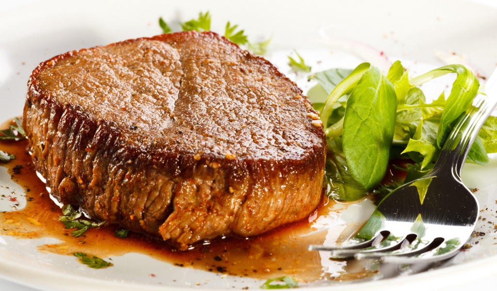 Отбивная с зеленым салатом на тарелке с вилкой