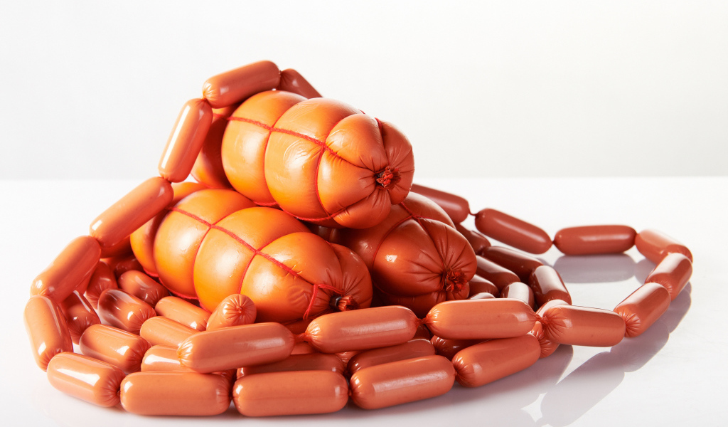 Свежие сосиски и колбаса на белом фоне