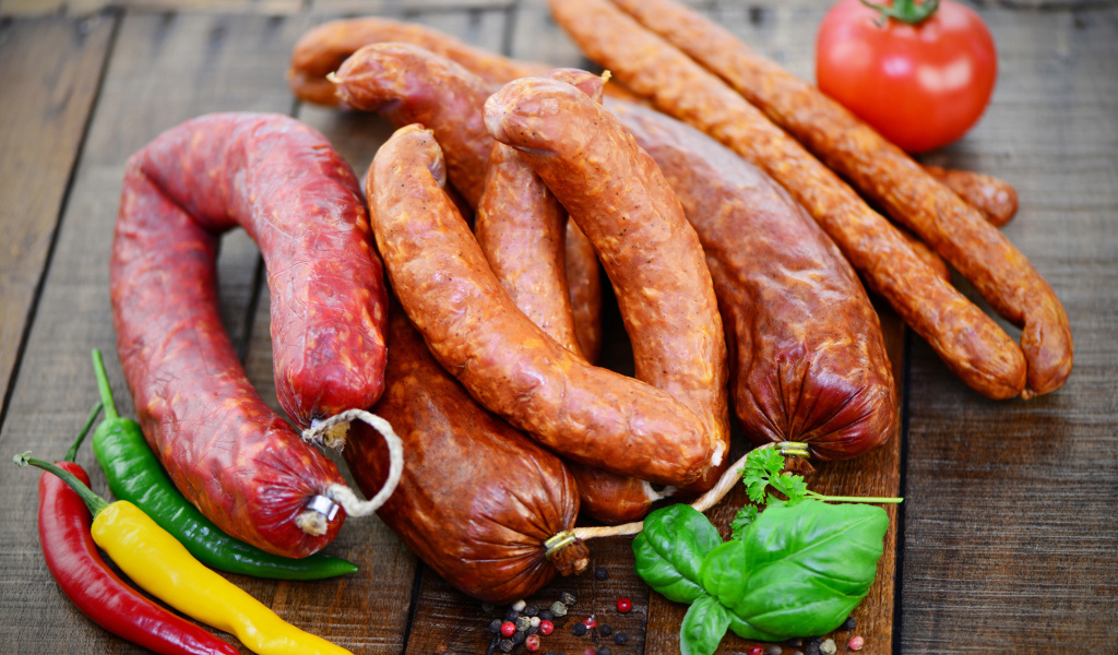 Свежие колбасы с перцем на столе