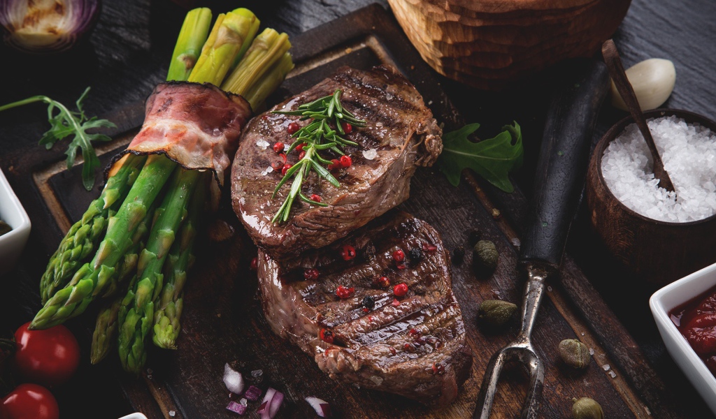 Жареное мясо с зеленой спаржей на столе 