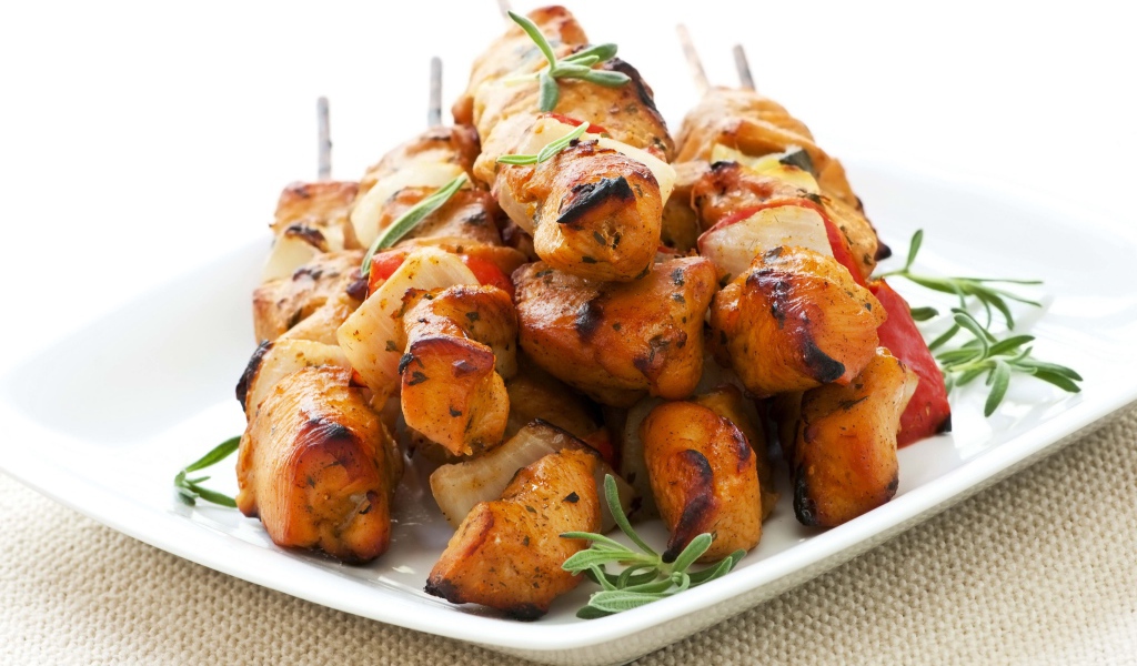Шашлыки на белой тарелке с зеленью розмарина