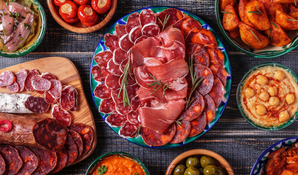 Большая тарелка с мясной нарезкой в центре праздничного стола