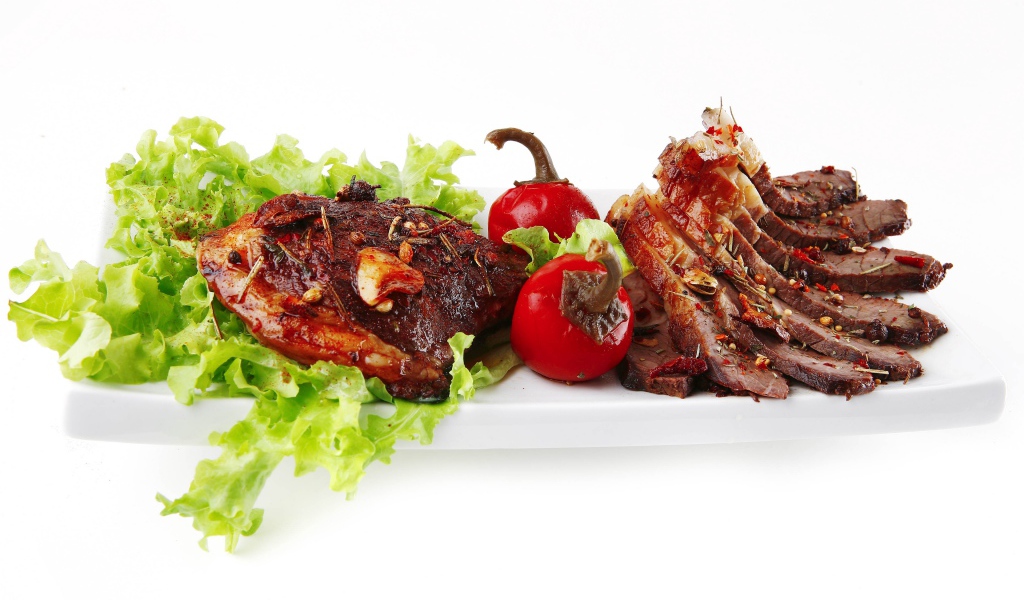 Мясо с листьями салата и красным перцем на белом фоне