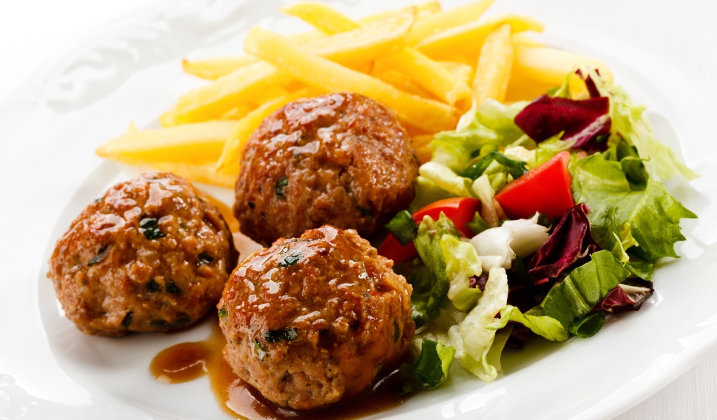Тефтели с картофелем фри и салатом на белой тарелке 