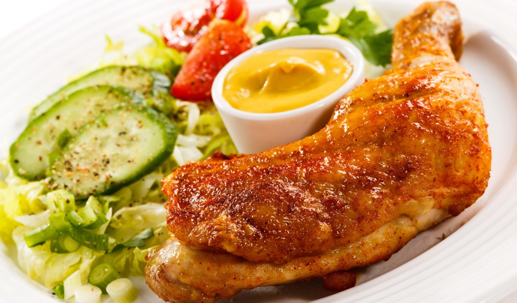 Жареная куриная ножка с овощами и соусом на тарелке