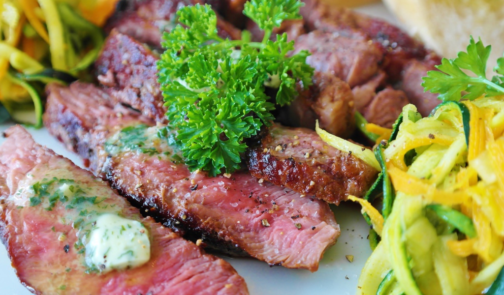 Нарезанный аппетитный кусок мяса с салатом и зеленью петрушки