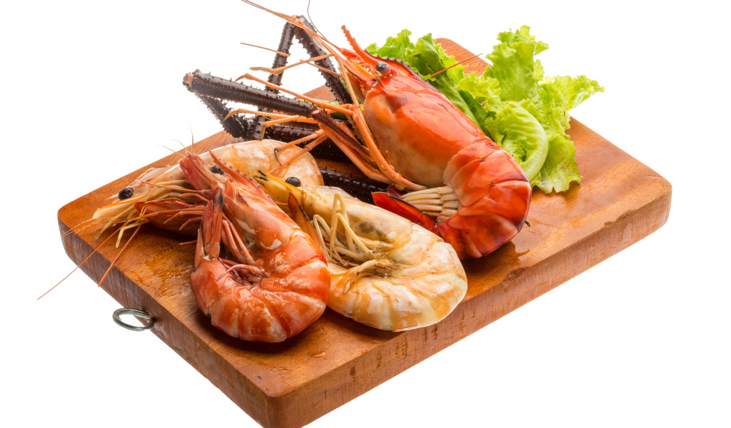 Вареные креветки с листьями салата на разделочной доске