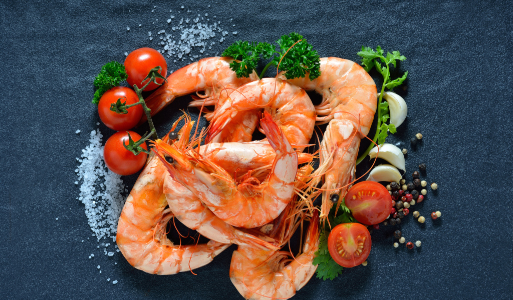 Вареные креветки на столе со специями и  помидорами 