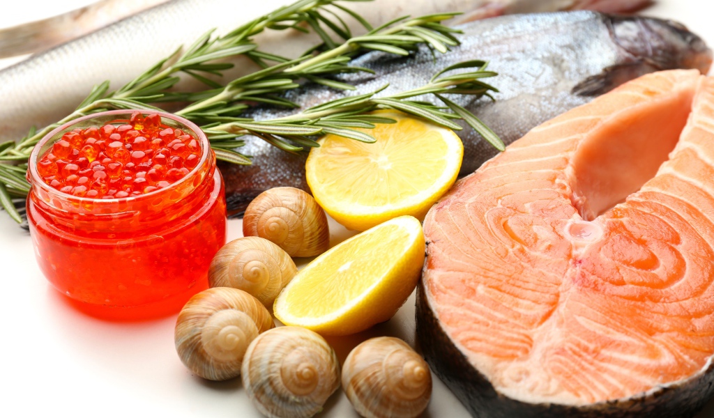 Красная рыба с улитками и красной икрой на столе с лимоном и базиликом