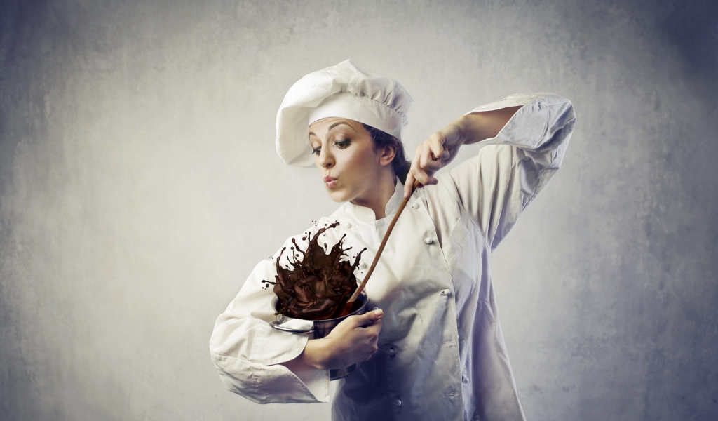 Женщина повар мешает шоколад в посуде на сером фоне