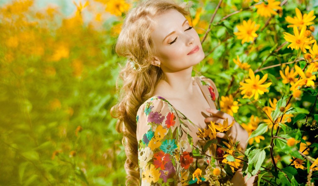 Красивая блондинка нежится в лучах солнца у желтых цветов