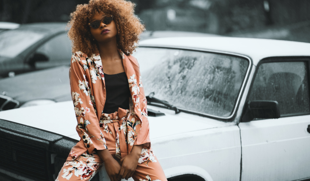 Красивая темнокожая девушка сидит на автомобиле 