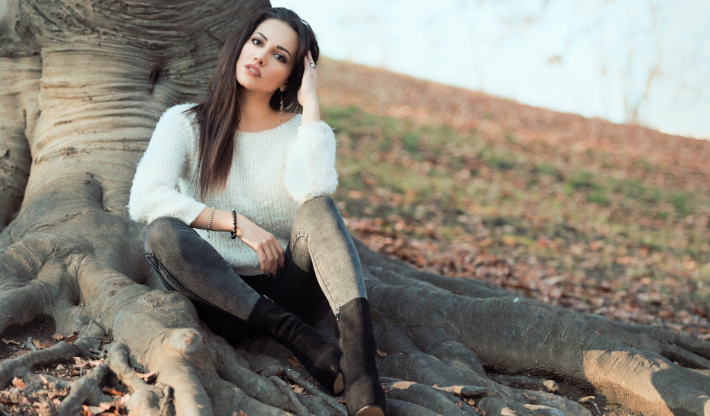 Красивая девушка сидит у дерева