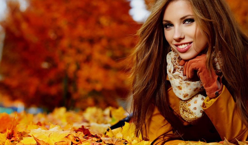 Красивая девушка лежит на опавших осенних листьях