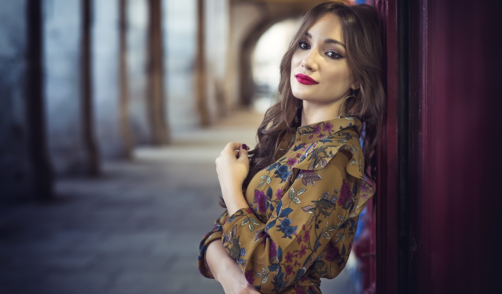 Девушка шатенка в красивом платье у стены