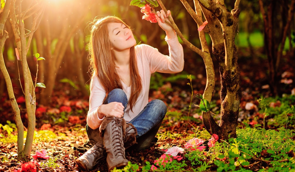 Девушка сидит на земле под ярким солнцем в лесу