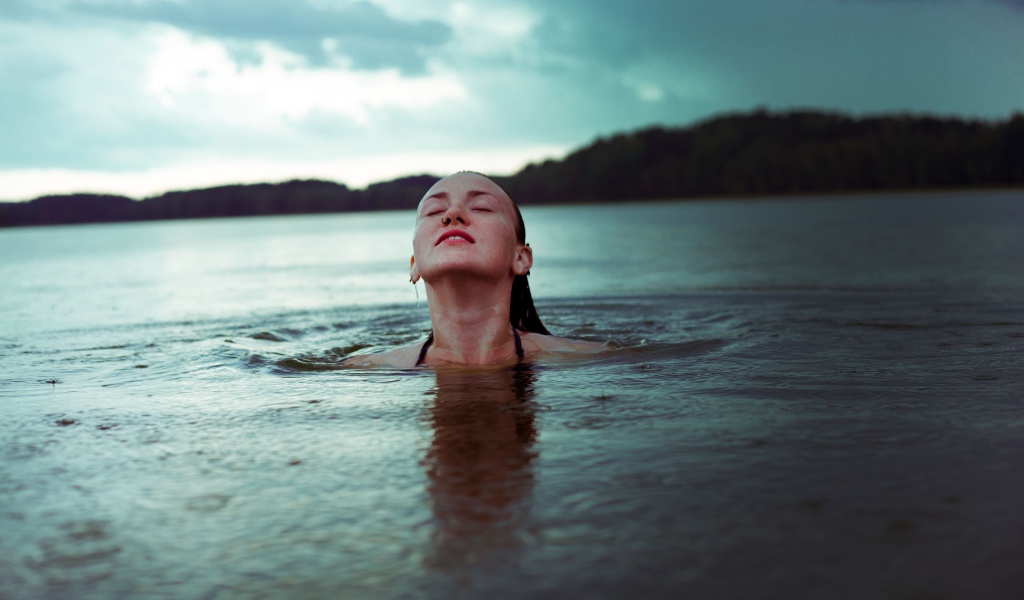 Молодая девушка купается в озере 