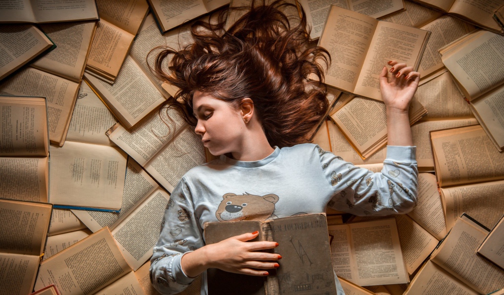 Молодая девушка спит на книгах
