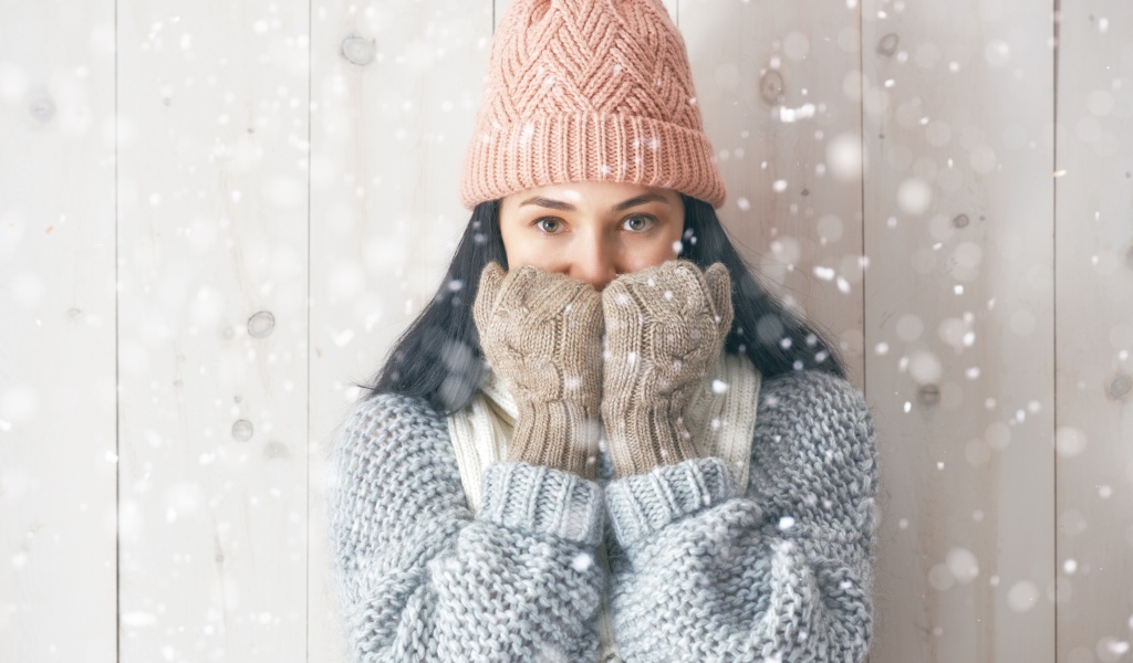 Молодая девушка с теплом свитере с шапкой на голове и перчатках