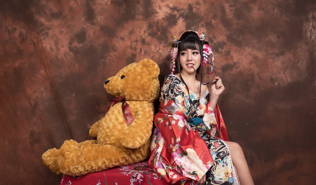 Девушка азиатка сидит с большим плюшевым медведем