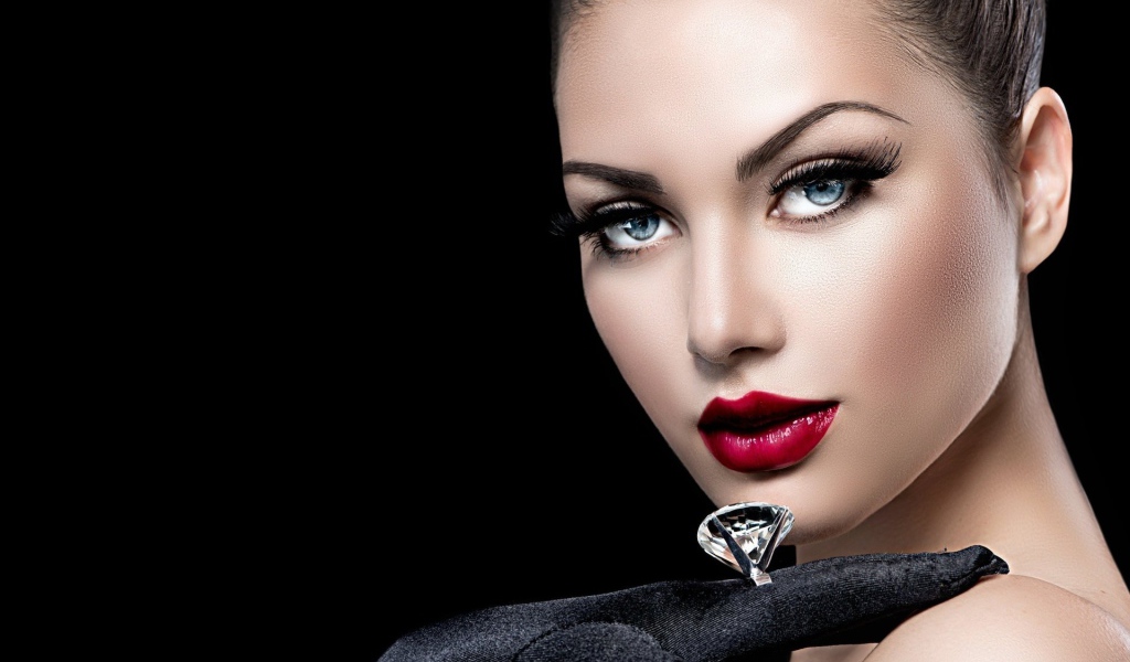 Beautiful blue-eyed girl with a ring on her finger on a black background