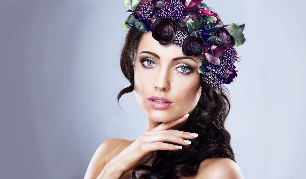 Красивая голубоглазая девушка с венком на голове на сером фоне