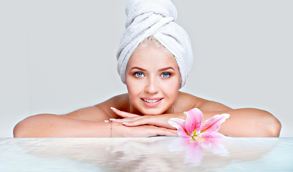 Красивая голубоглазая женщина в тюрбане с полотенца расслабляется в SPA