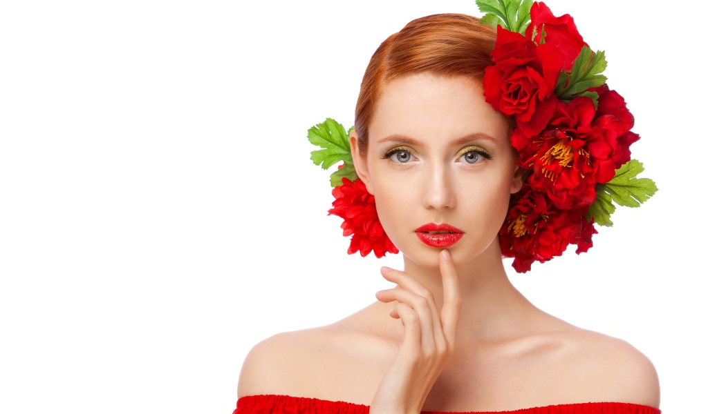 Красивая яркая девушка с красными цветами в волосах на белом фоне