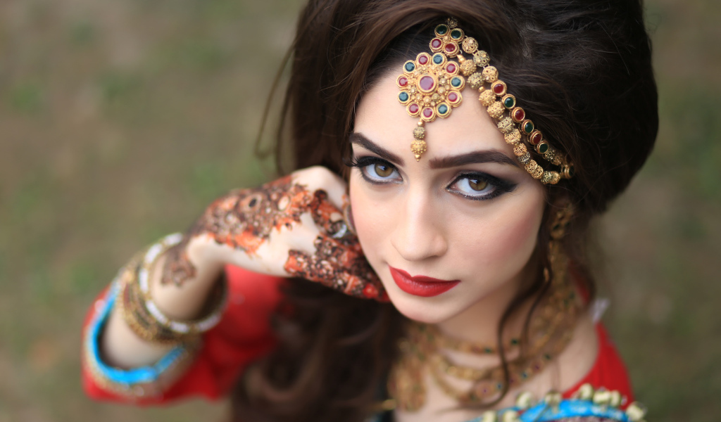 Красивая кареглазая девушка в индийском костюме с рисунками на руках 