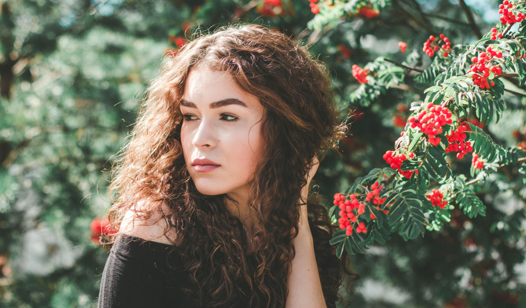 Красивая шатенка у ветки с красными ягодами рябины