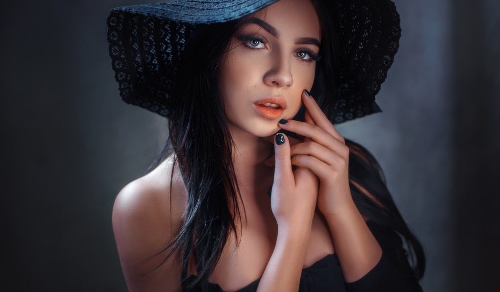 Красивая брюнетка в большой черной шляпе 