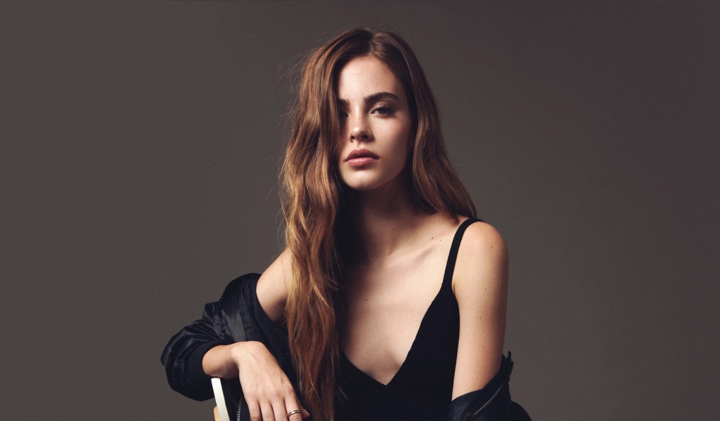 Красивая брюнетка в черном платье сидит на стуле